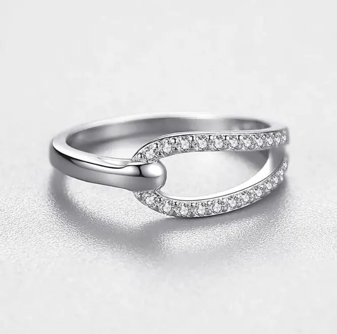 Close-up of the Seraph Loop Ring in sterling silver, featuring a delicate open-loop design with pavé stones. A refined and timeless fashion accessory.