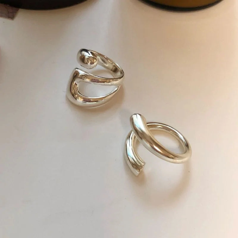 Two Lyra Rings in 925 sterling silver showcasing unique, modern designs with smooth, polished surfaces on a white background.
