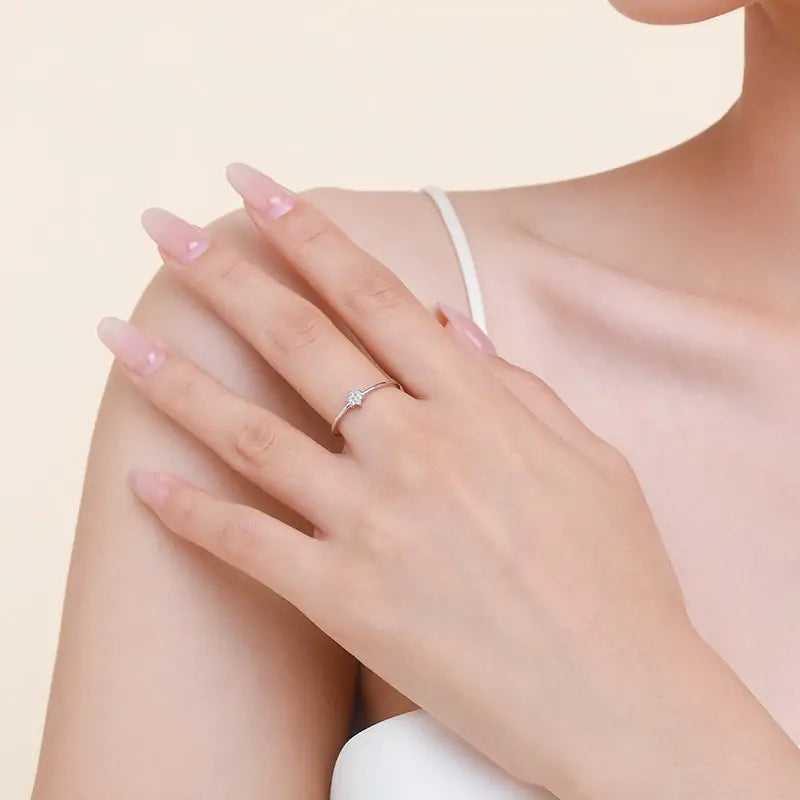 Woman wearing a delicate sterling silver star ring with sparkling cubic zirconia. A refined accessory perfect for adding subtle elegance to any outfit.