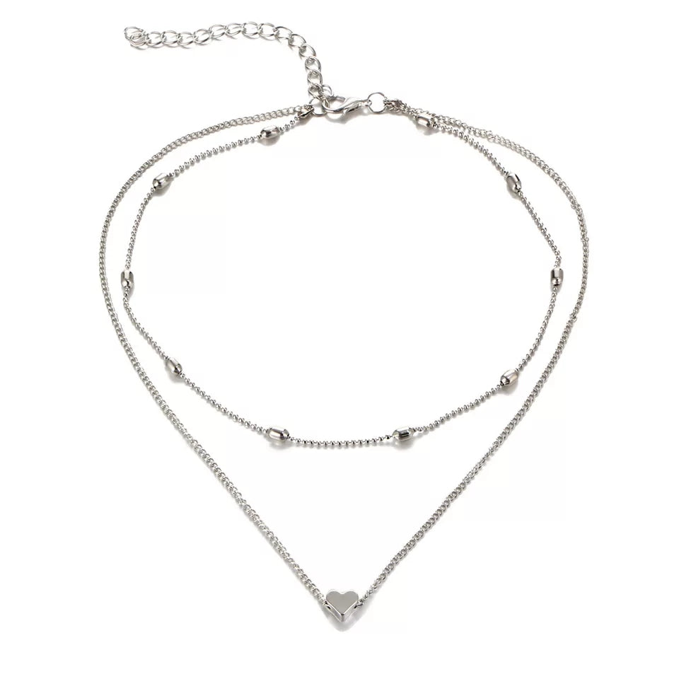 Silver Fiora Heart Necklace with layered chains, featuring a delicate heart charm and adjustable clasp for a timeless jewelry accessory.