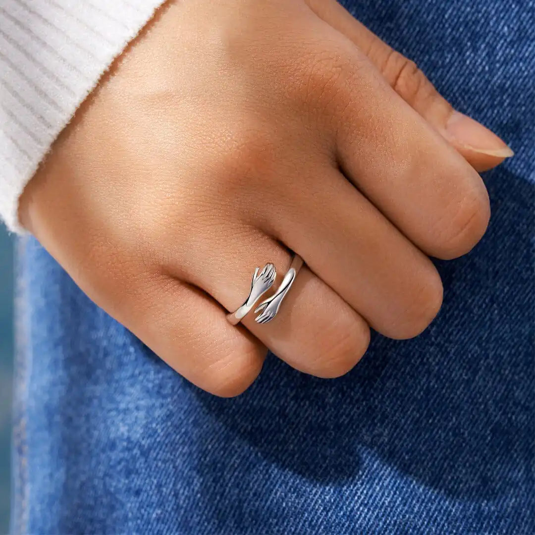 Silver Hug Ring worn on a hand, showcasing its elegant design of two hands embracing. A stylish and symbolic jewelry piece for any occasion.